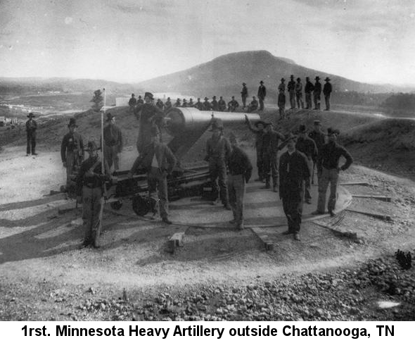 1rst. Minnesota Heavy Artillery outside Chattanooga, TN; photograph showing several soldiers standing around a large cannon on a stationary mount with a view of a town, river and high hill behind them